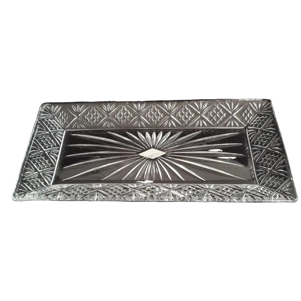 A rectangular cut glass platter with a geometric pattern and a central sunburst design, photographed against a black fabric background.
